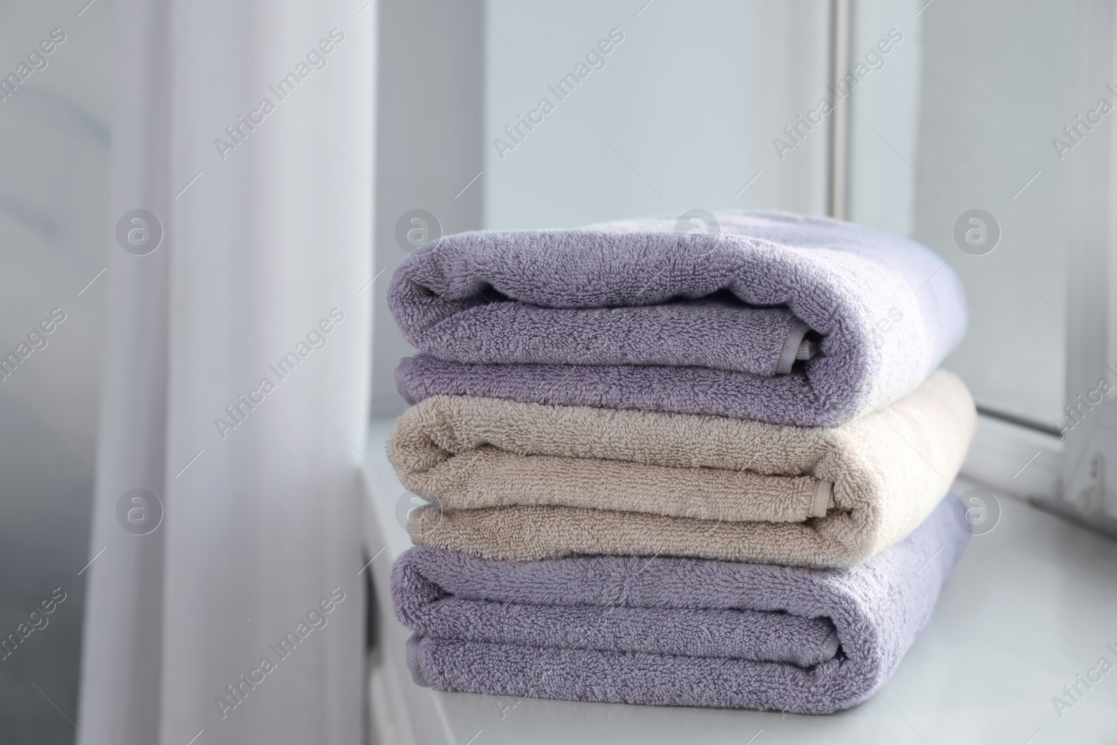 Photo of Stack of fresh towels on windowsill. Space for text