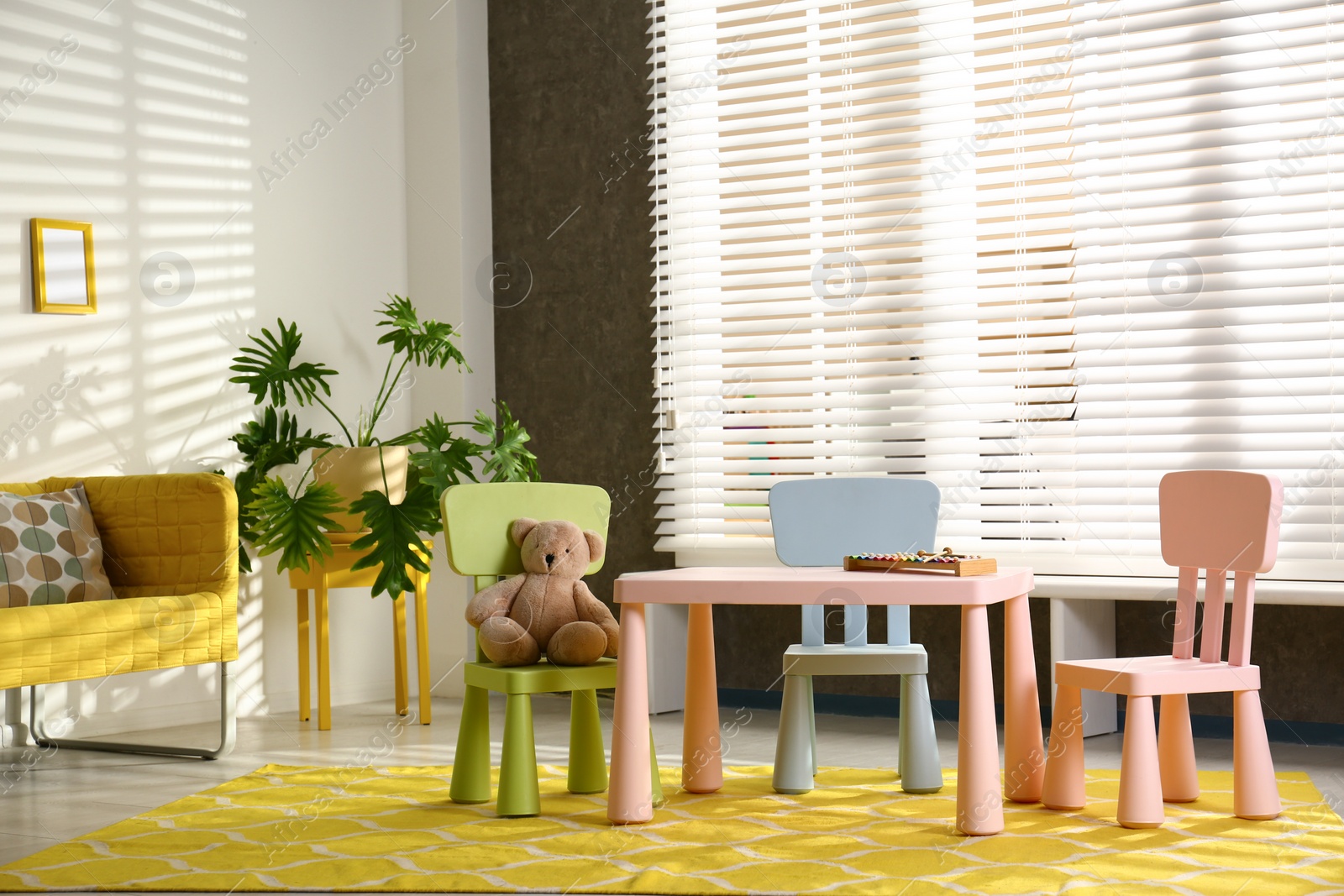 Photo of Stylish playroom interior with table, chairs and sofa