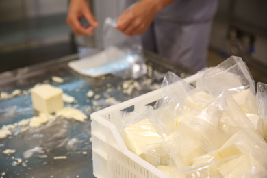Photo of Box with packed feta cheese at factory and blurred worker on background, closeup