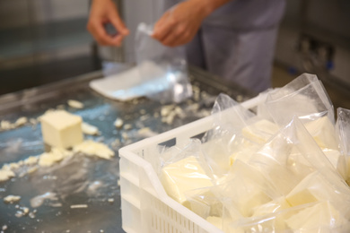 Box with packed feta cheese at factory and blurred worker on background, closeup