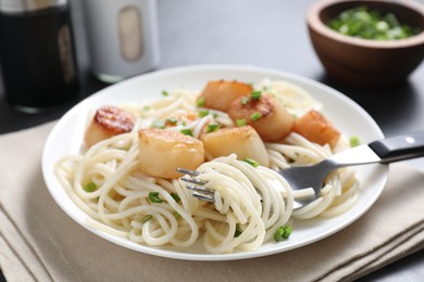 Delicious scallop pasta with green onion served on grey table, closeup