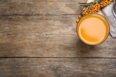 Delicious sea buckthorn juice on wooden table, top view. Space for text