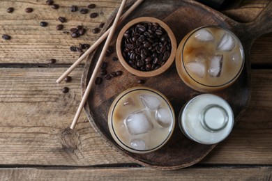 Photo of Refreshing iced coffee with milk in glasses, ingredients and straws on wooden table, top view. Space for text