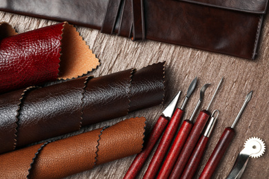 Photo of Leather samples and tools on brown table, flat lay