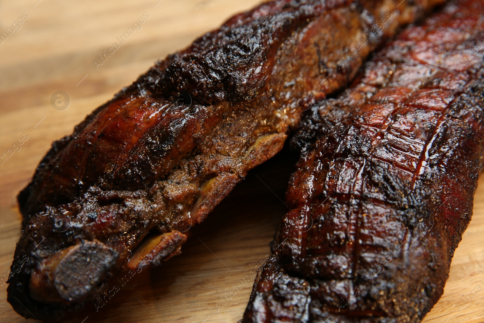 Photo of Tasty grilled pork ribs on wooden board, closeup