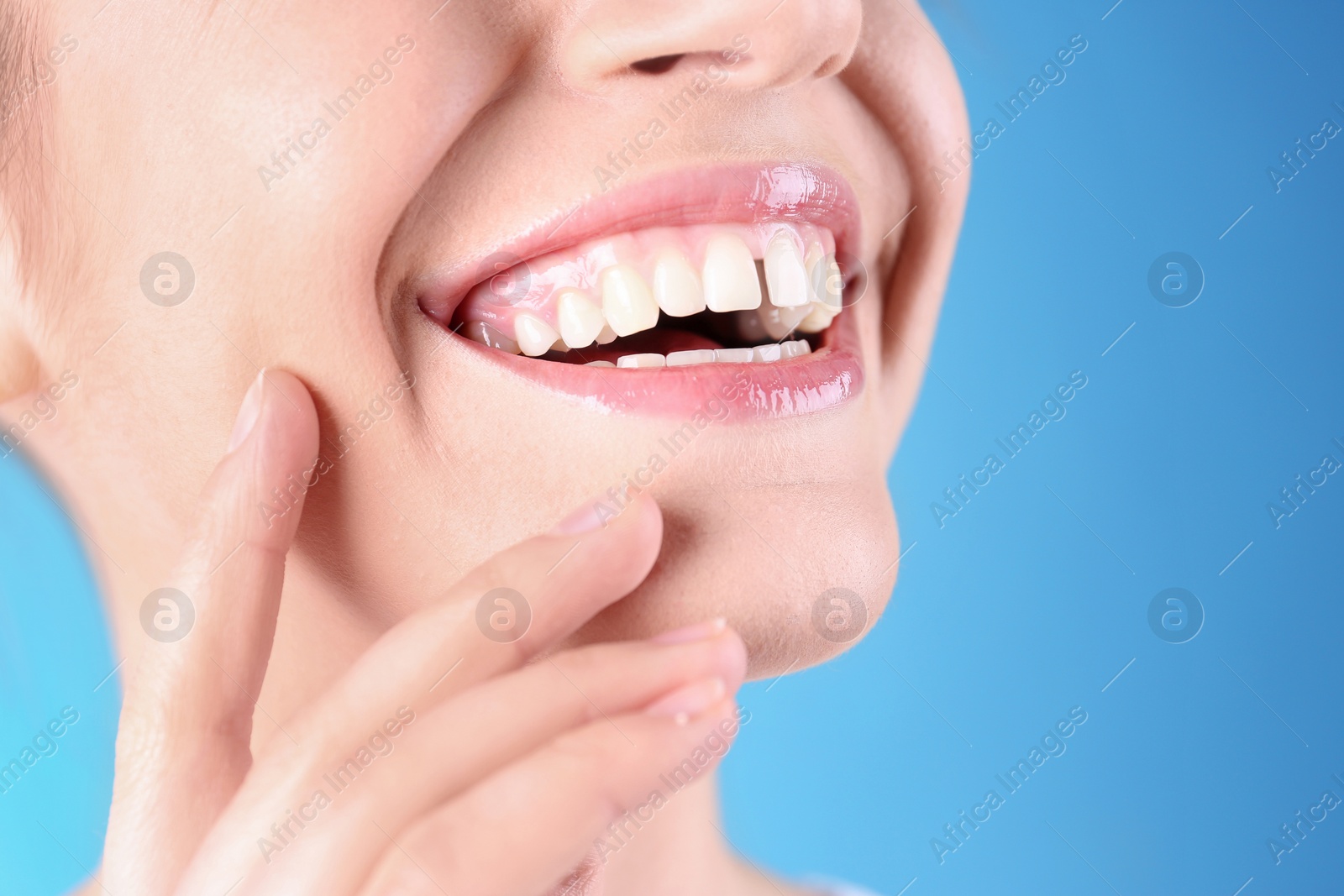 Image of Woman with diastema between upper front teeth on light blue background, closeup