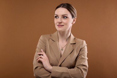 Beautiful woman with elegant necklace on brown background