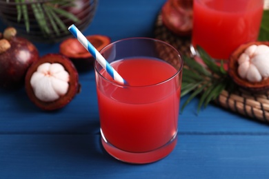 Photo of Delicious fresh mangosteen juice on blue wooden table