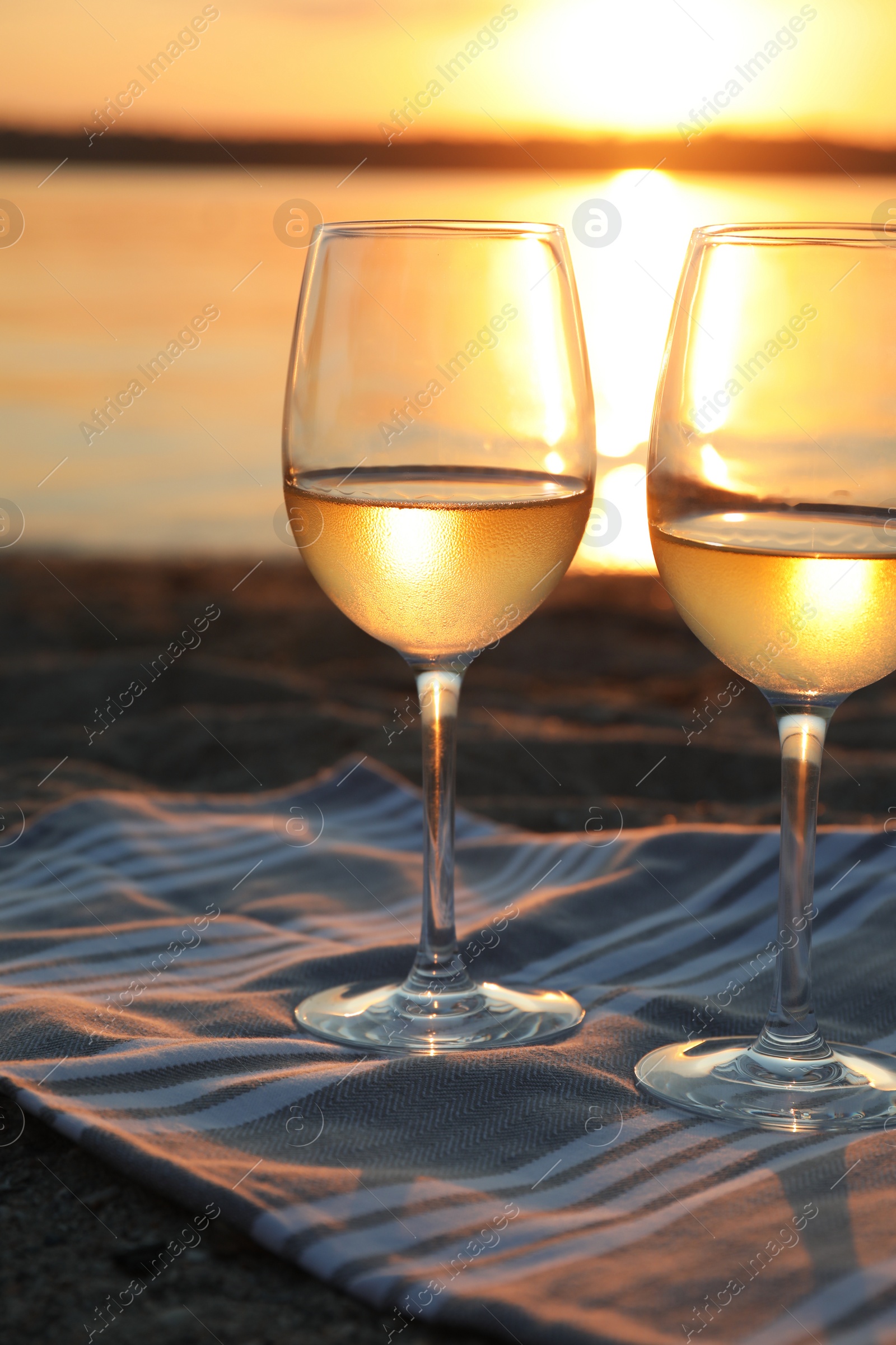 Photo of Glasses of delicious wine on riverside at sunset