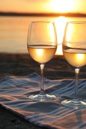 Photo of Glasses of delicious wine on riverside at sunset