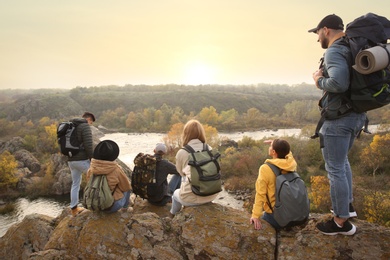 Group of friends with backpacks enjoying beautiful view near mountain river