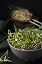Photo of Mung bean sprouts in bowl on black table, closeup