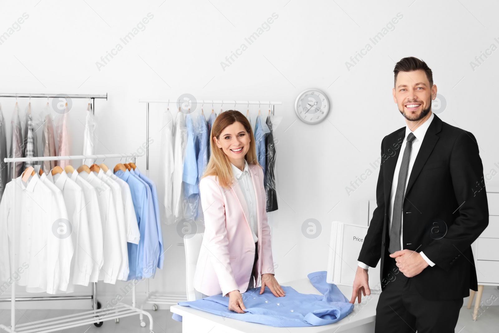 Photo of Young businessman giving shirt to dry-cleaner's worker