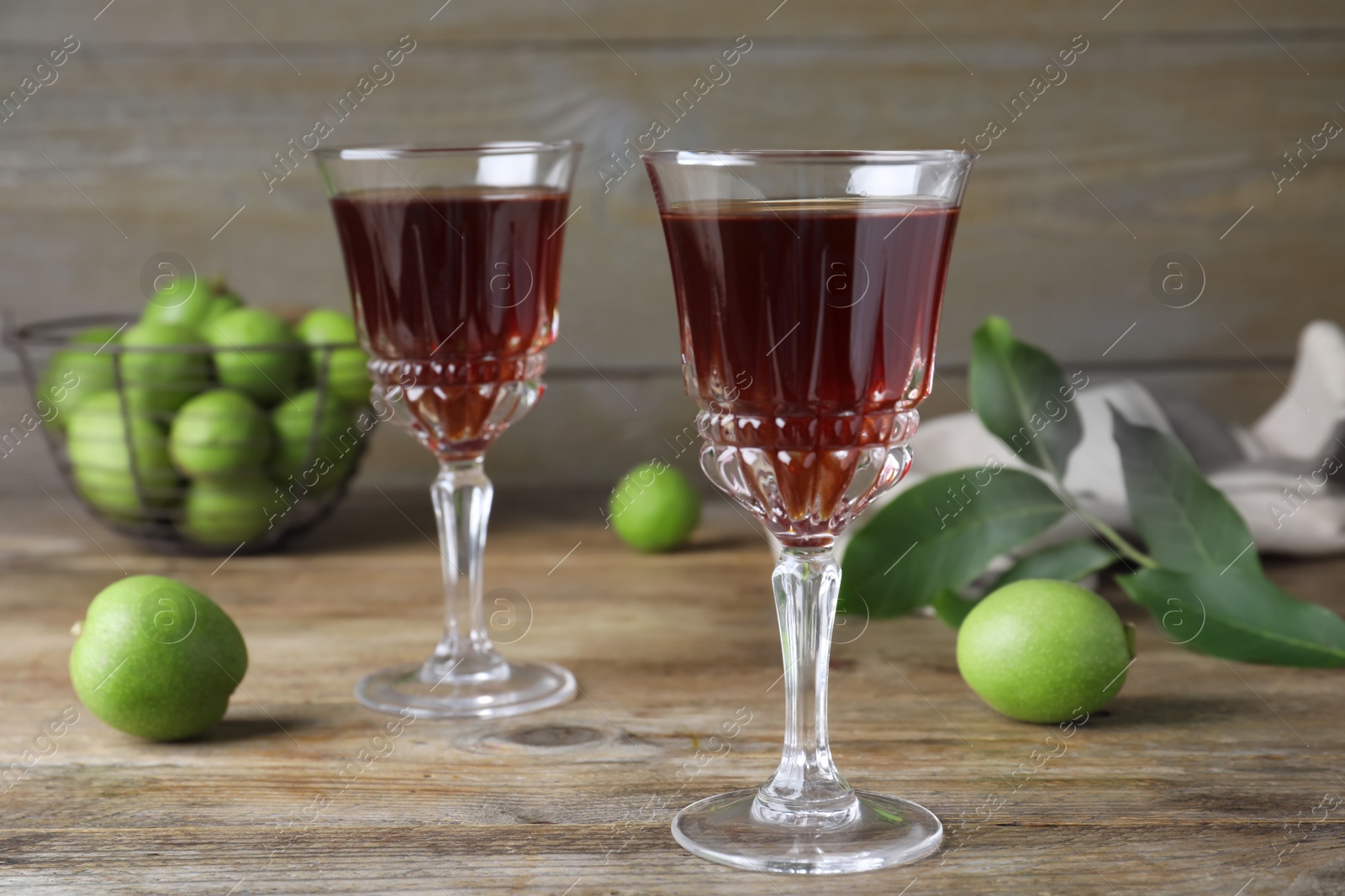 Photo of Delicious liqueur and green walnuts on wooden table