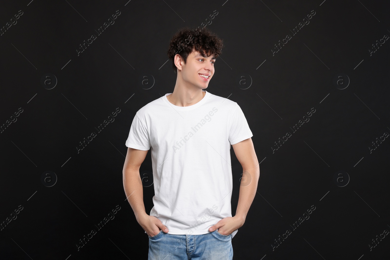 Photo of Man wearing white t-shirt on black background. Mockup for design