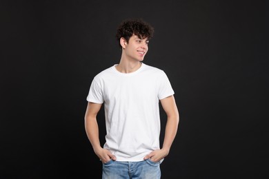 Photo of Man wearing white t-shirt on black background. Mockup for design