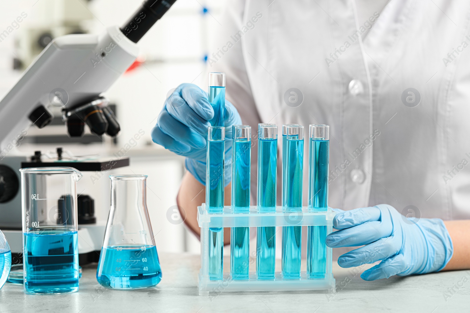 Photo of Scientist taking test tube with light blue liquid in laboratory, closeup