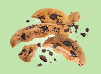 Image of Tasty chocolate chip cookies falling on pastel green background