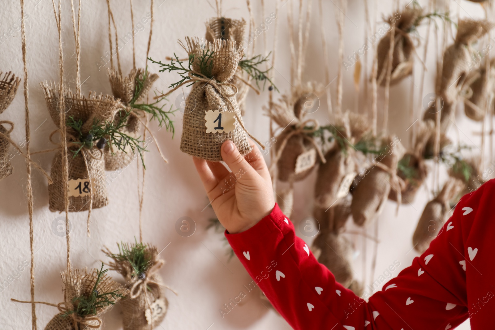 Photo of Little girl taking gift from Christmas advent calendar indoors, closeup