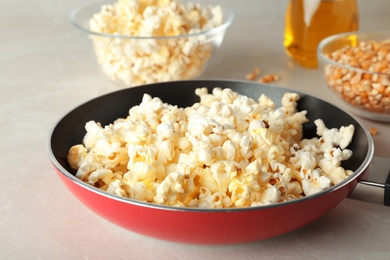 Frying pan with tasty popcorn on table