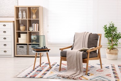 Photo of Stylish living room interior with comfortable armchair and blanket