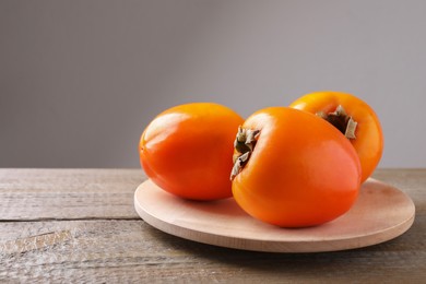 Delicious ripe persimmons on wooden table. Space for text