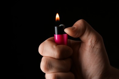 Photo of Man holding pink lighter on black background, closeup