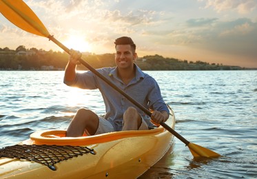 Photo of Happy man kayaking on river at sunset. Summer activity