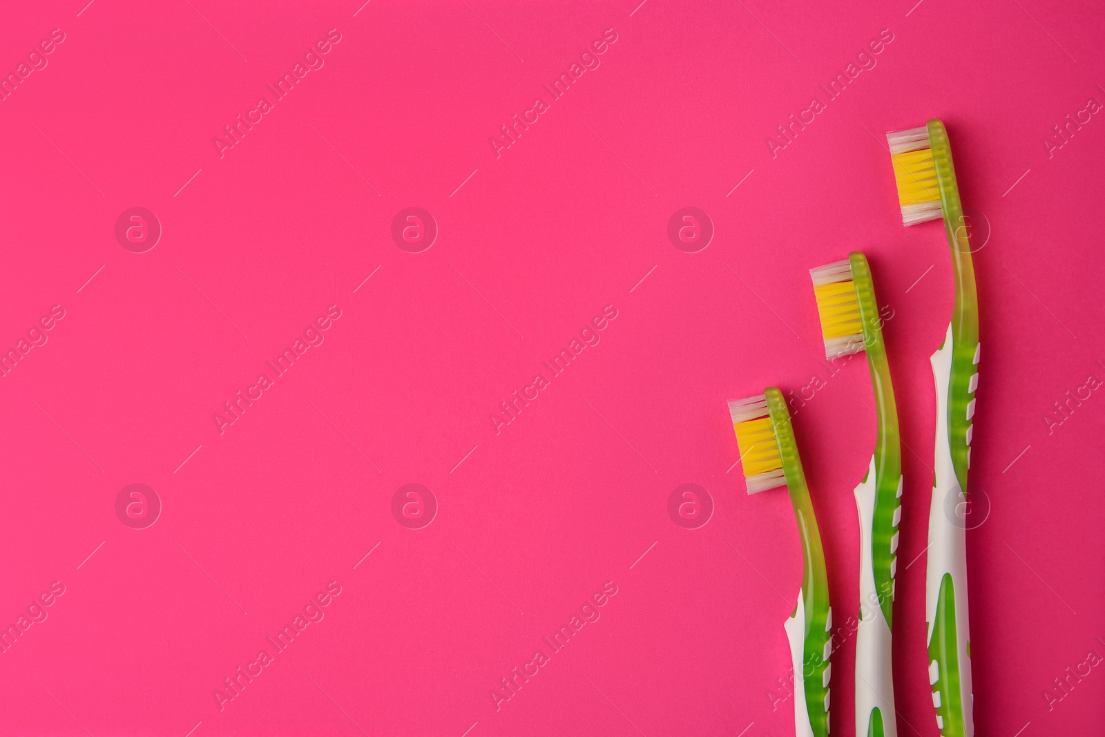 Photo of Toothbrushes on pink background, flat lay. Space for text