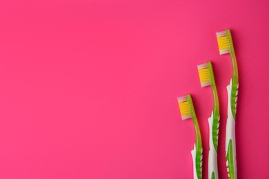 Photo of Toothbrushes on pink background, flat lay. Space for text