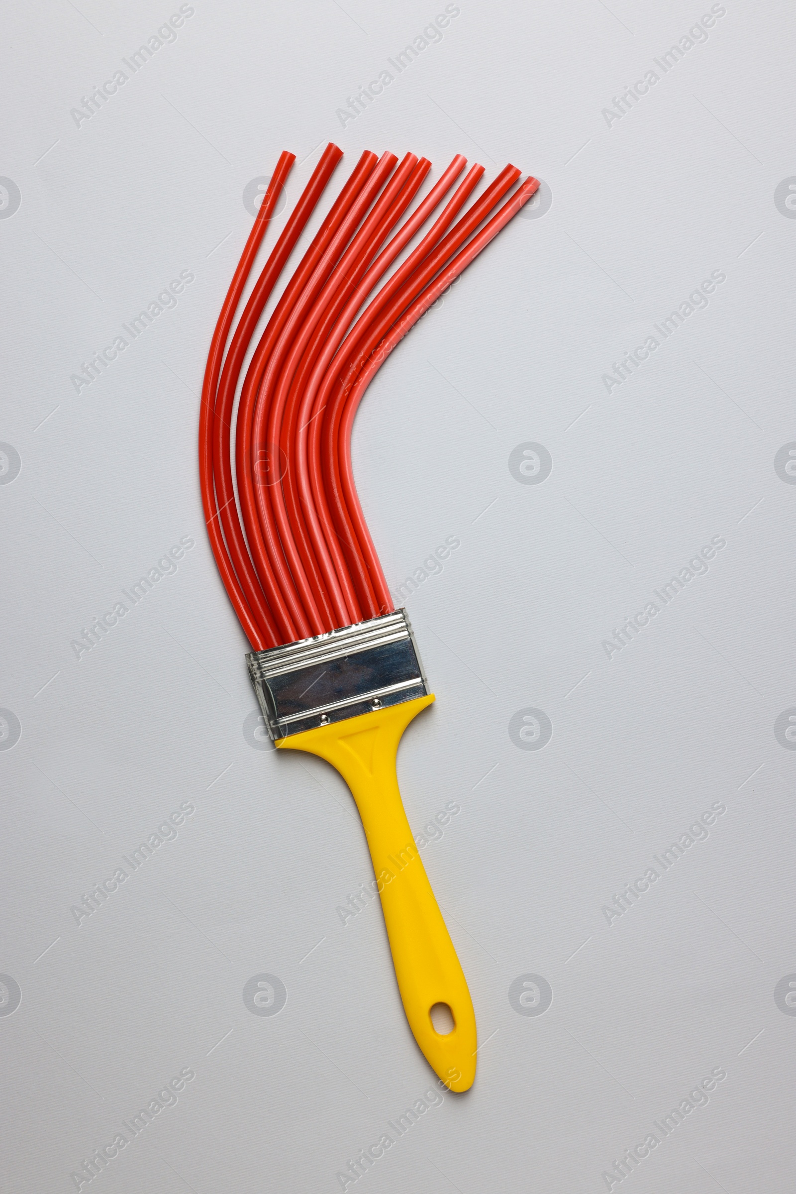 Photo of Brush with red straws on light grey background, top view. Creative concept