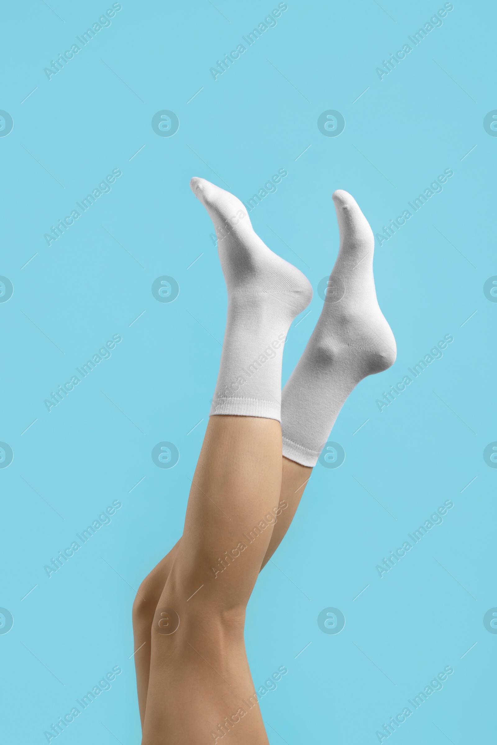 Photo of Woman in stylish white socks on light blue background, closeup