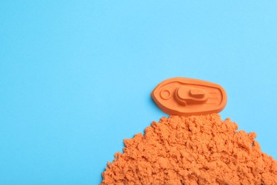 Photo of Orange kinetic sand on light blue background, flat lay. Space for text