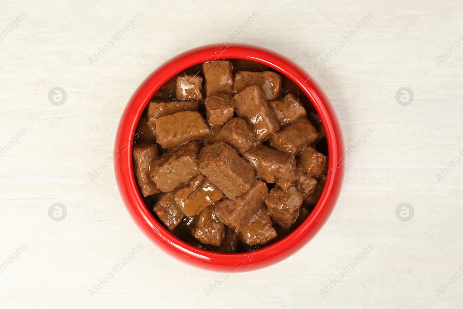 Photo of Wet pet food in feeding bowl on white table, top view