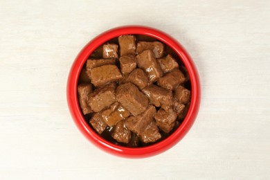 Photo of Wet pet food in feeding bowl on white table, top view