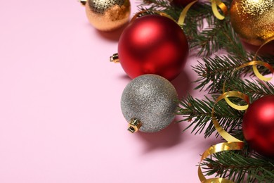 Shiny Christmas balls, streamers and fir tree branches on pink background, closeup. Space for text