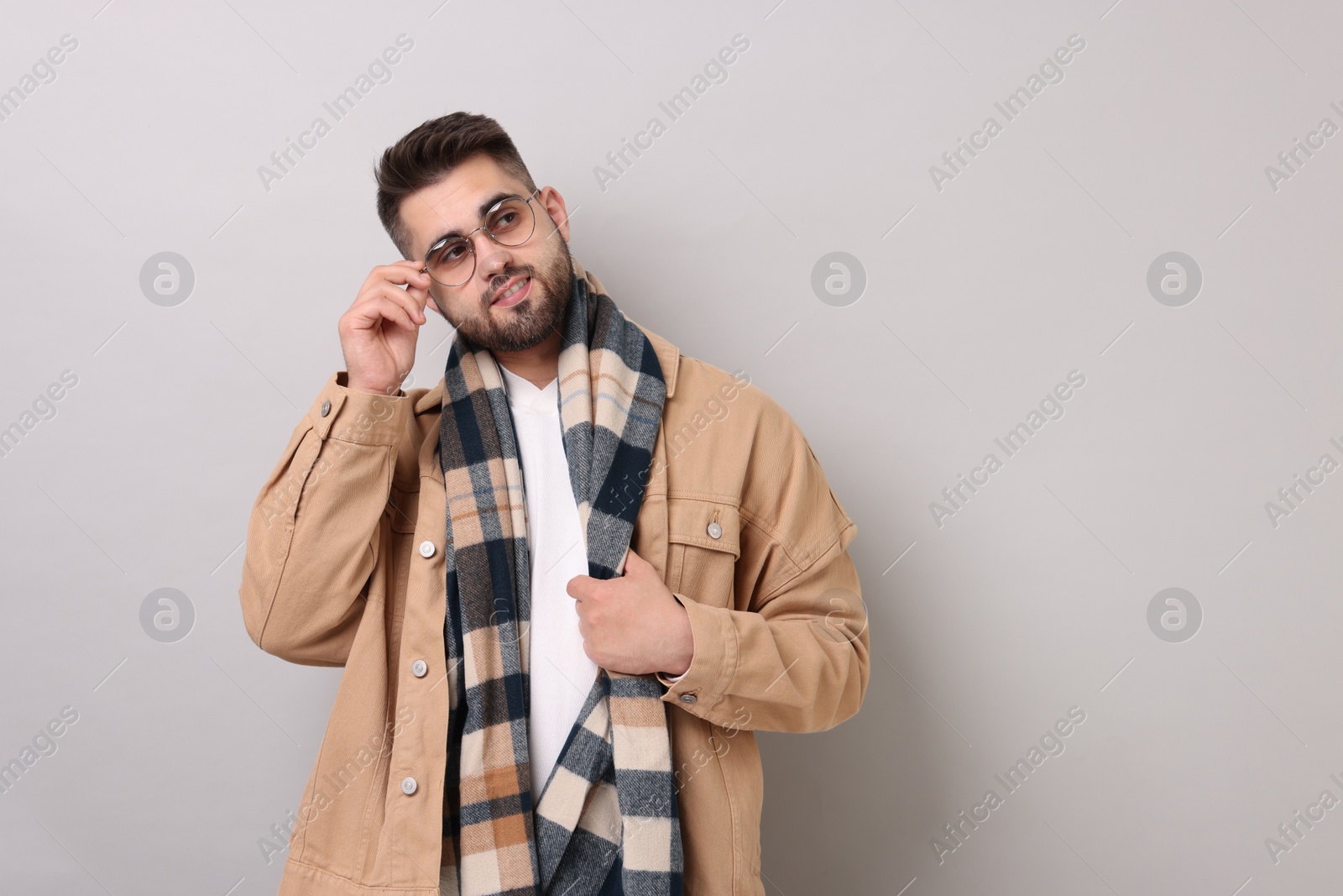 Photo of Handsome man in warm scarf on light grey background. Space for text