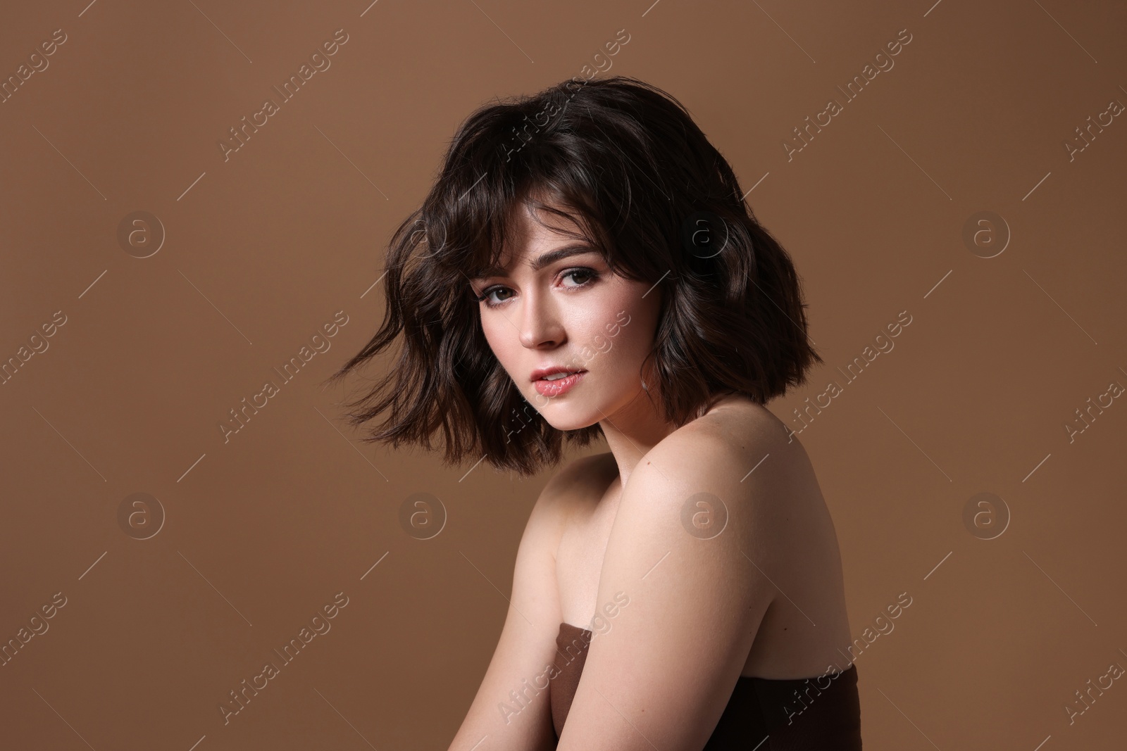 Photo of Portrait of beautiful young woman with wavy hairstyle on brown background