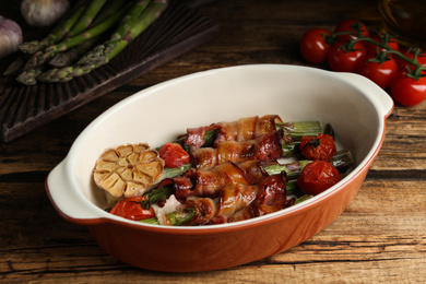 Oven baked asparagus wrapped with bacon in ceramic dish on wooden table