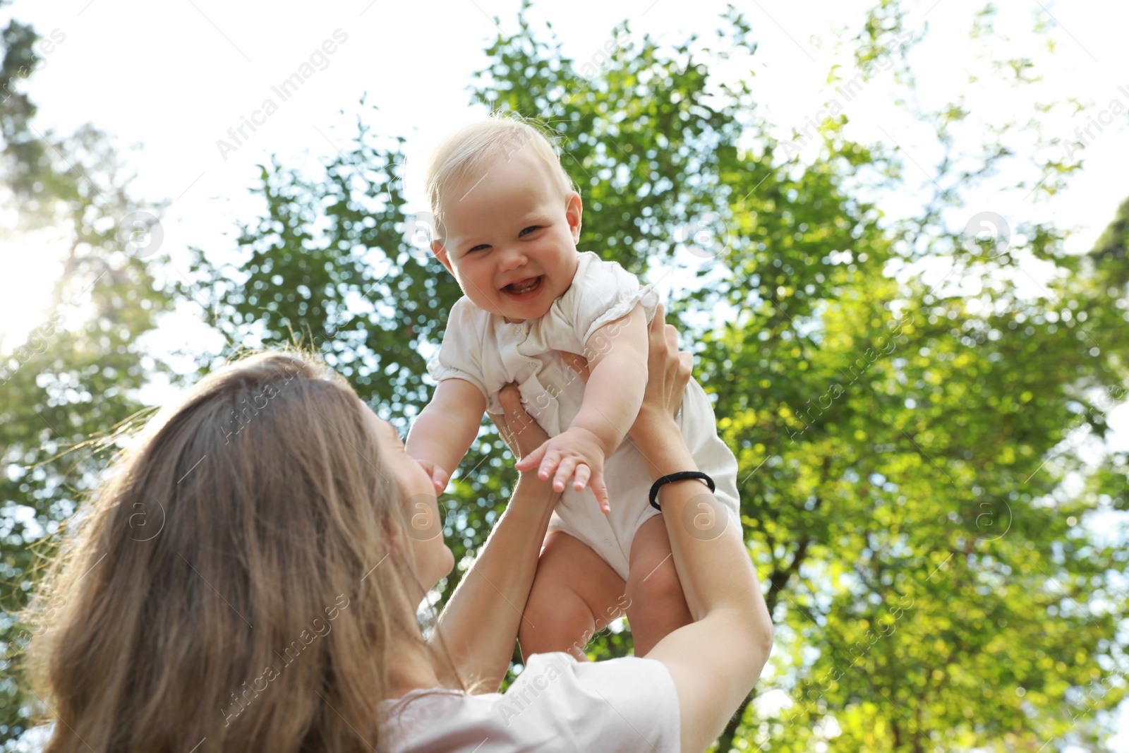 Photo of Mother with her cute baby spending time together outdoors, low angle view