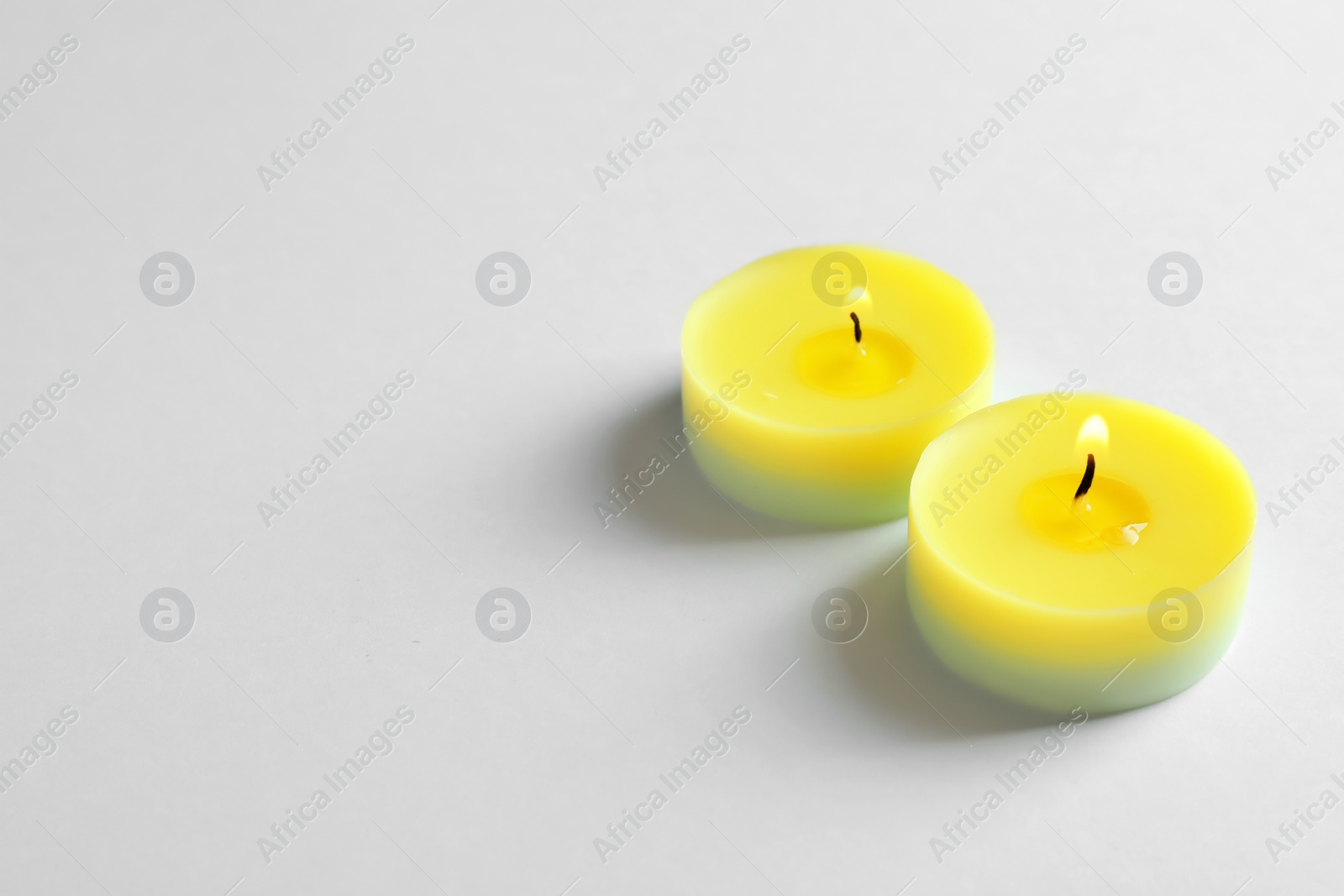 Photo of Colorful wax candles burning on white background