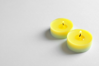 Colorful wax candles burning on white background