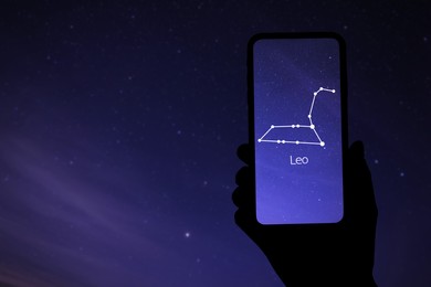 Image of Woman using stargazing app on her phone at night, closeup. Identified stick figure pattern of Lion (Leo) constellation on device screen