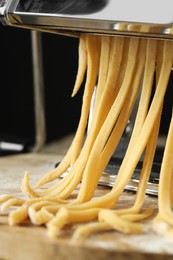 Photo of Pasta maker with raw dough on wooden table, closeup