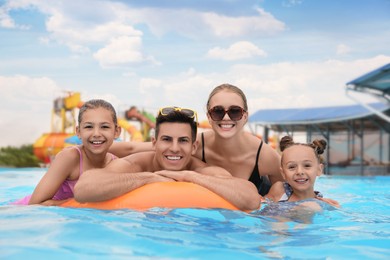 Photo of Happy family with inflatable ring in swimming pool at water park