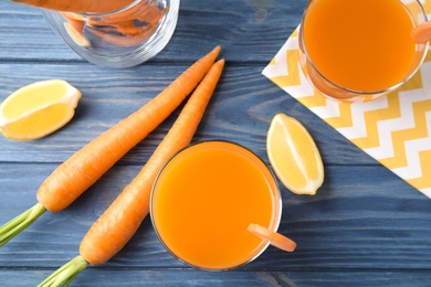 Photo of Glass with carrot juice and fresh vegetable on wooden table, top view
