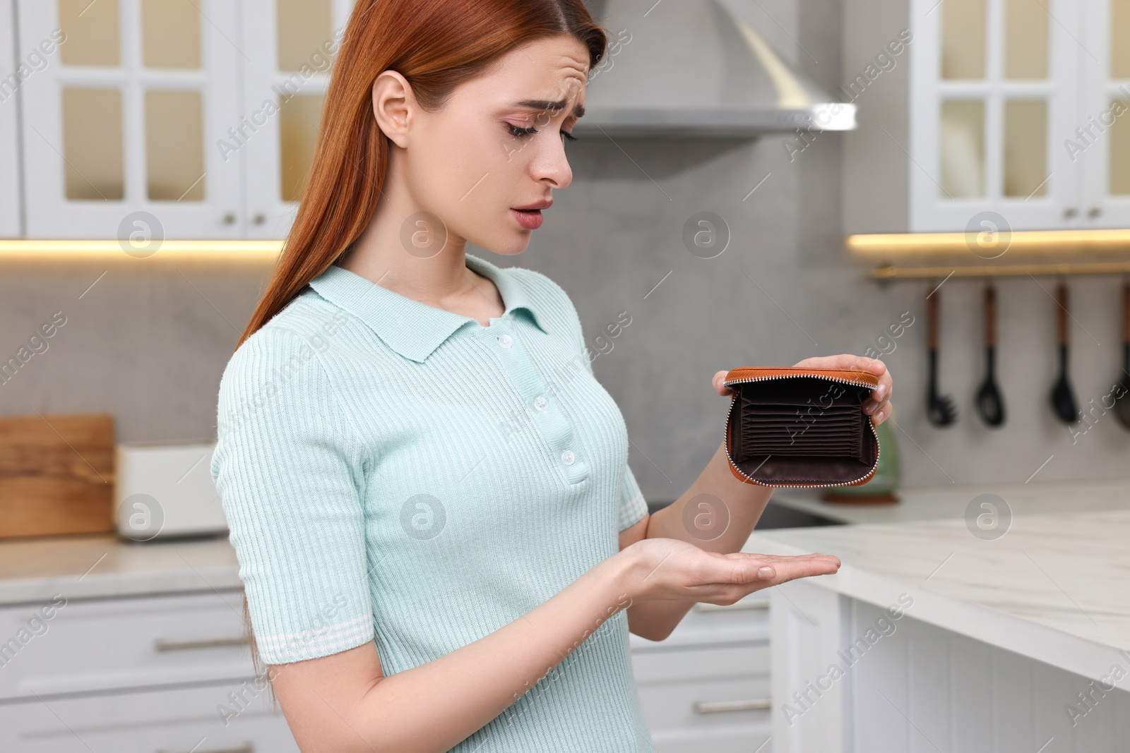 Photo of Upset woman with empty wallet at home