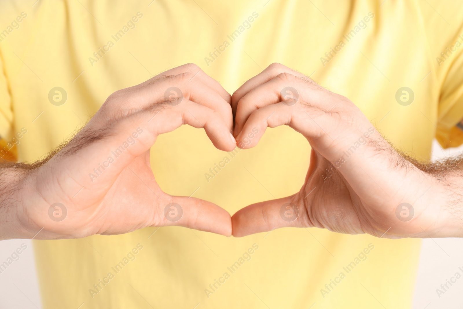 Photo of Young man making heart with hands, closeup