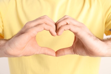 Young man making heart with hands, closeup