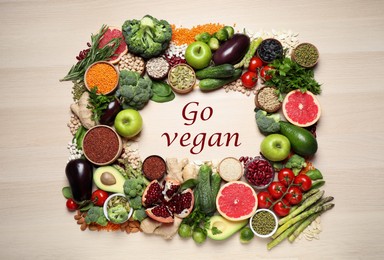 Image of Phrase Go Vegan and fresh products on wooden background, flat lay